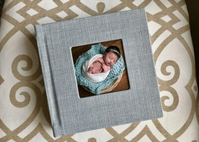 A gray photo album with a photo of a newborn baby.