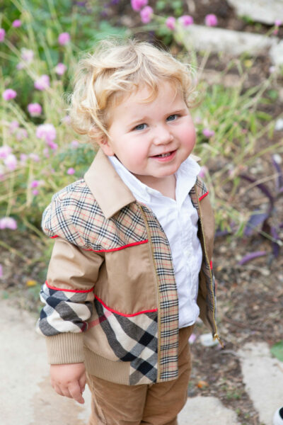 A little boy wearing a burberry jacket and pants.