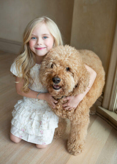 A little girl hugging a brown poodle.