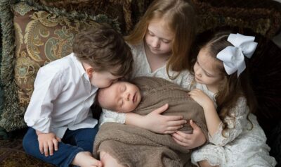 A group of children hugging a newborn baby captured by Jenn Brookover Photography.