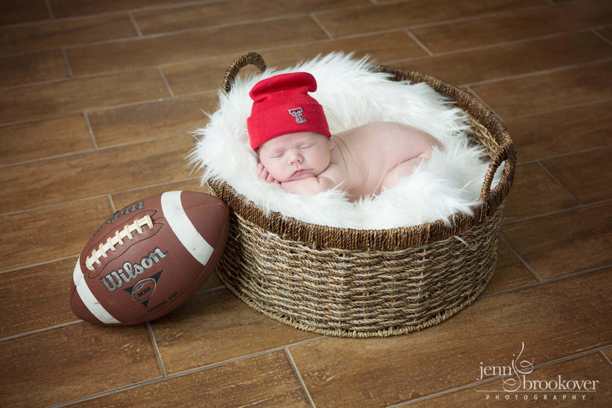 newborn boy in Texas Tech gear with football during photo session