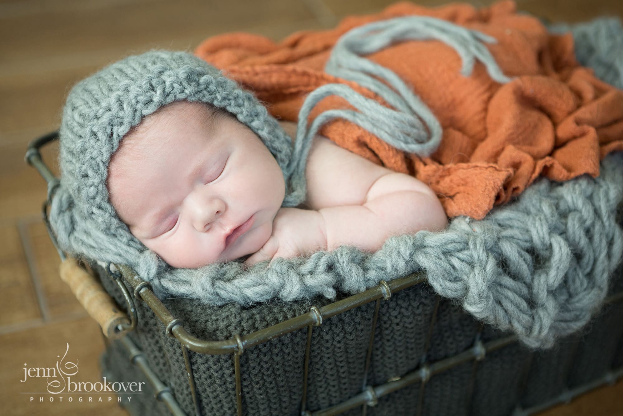 newborn boy in gray bonnet on knitted blanket