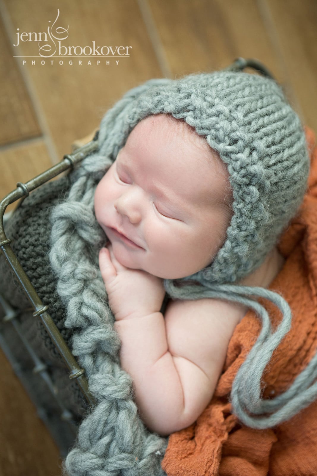 newborn boy in gray knitted cap and orange wrap