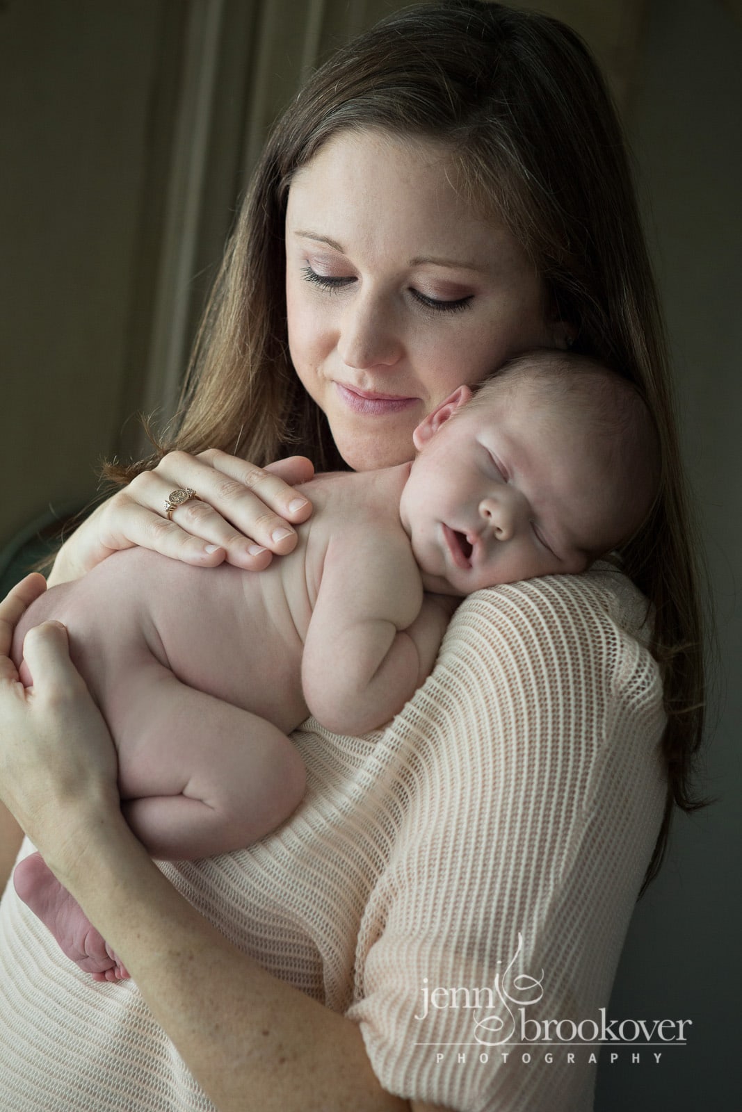 mom snuggling newborn baby boy at home in San Antonio 
