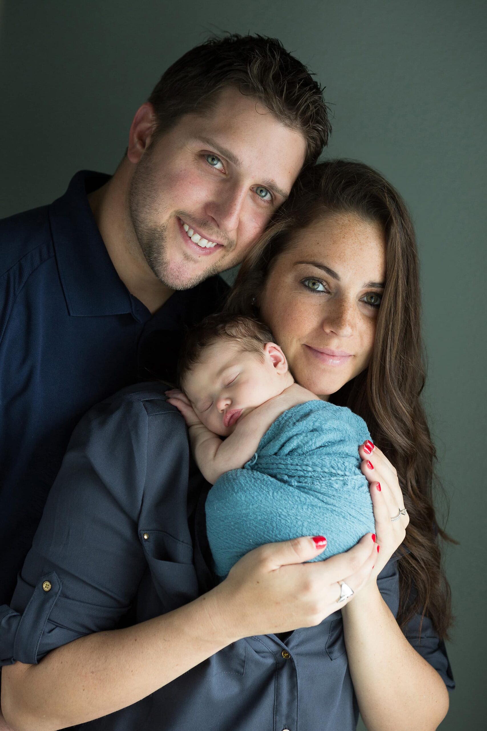 family of three, mom, dad and baby girl taken during newborn portrait session in their home