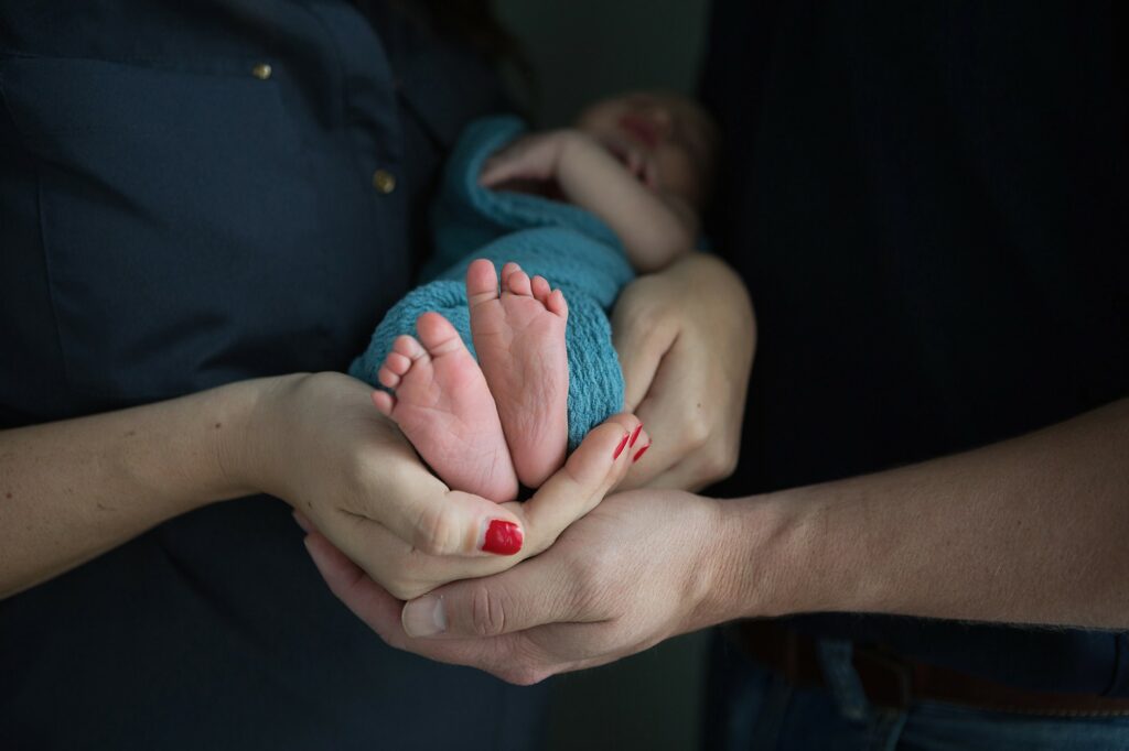 newborn feet close up in mom and dad's hands during portrait session at home