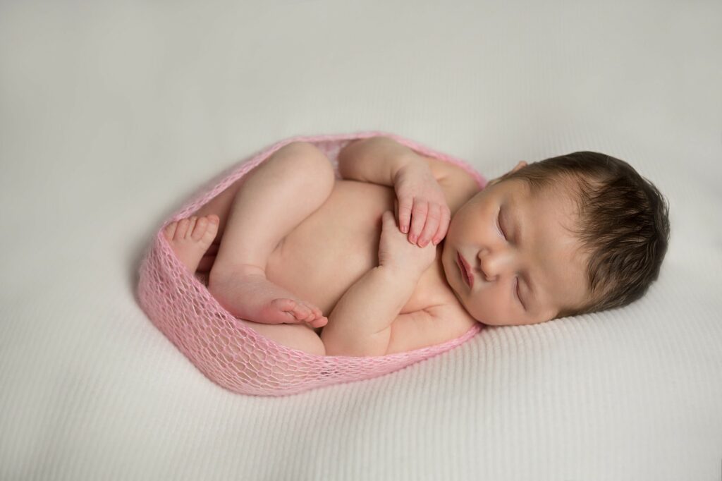 newborn wrapped up in pink mohair wrap curled up during photo session