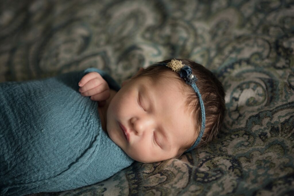 close up of newborn wrapped in teal wearing a Devoted Knits headband
