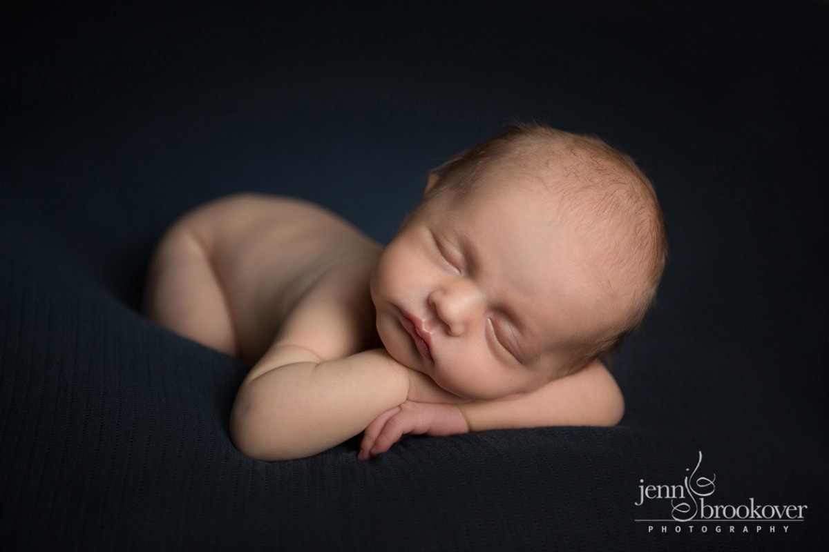 stunning newborn asleep on a blue blanket with his head on his hands at home in San Antonio, Texas with Jenn Brookover