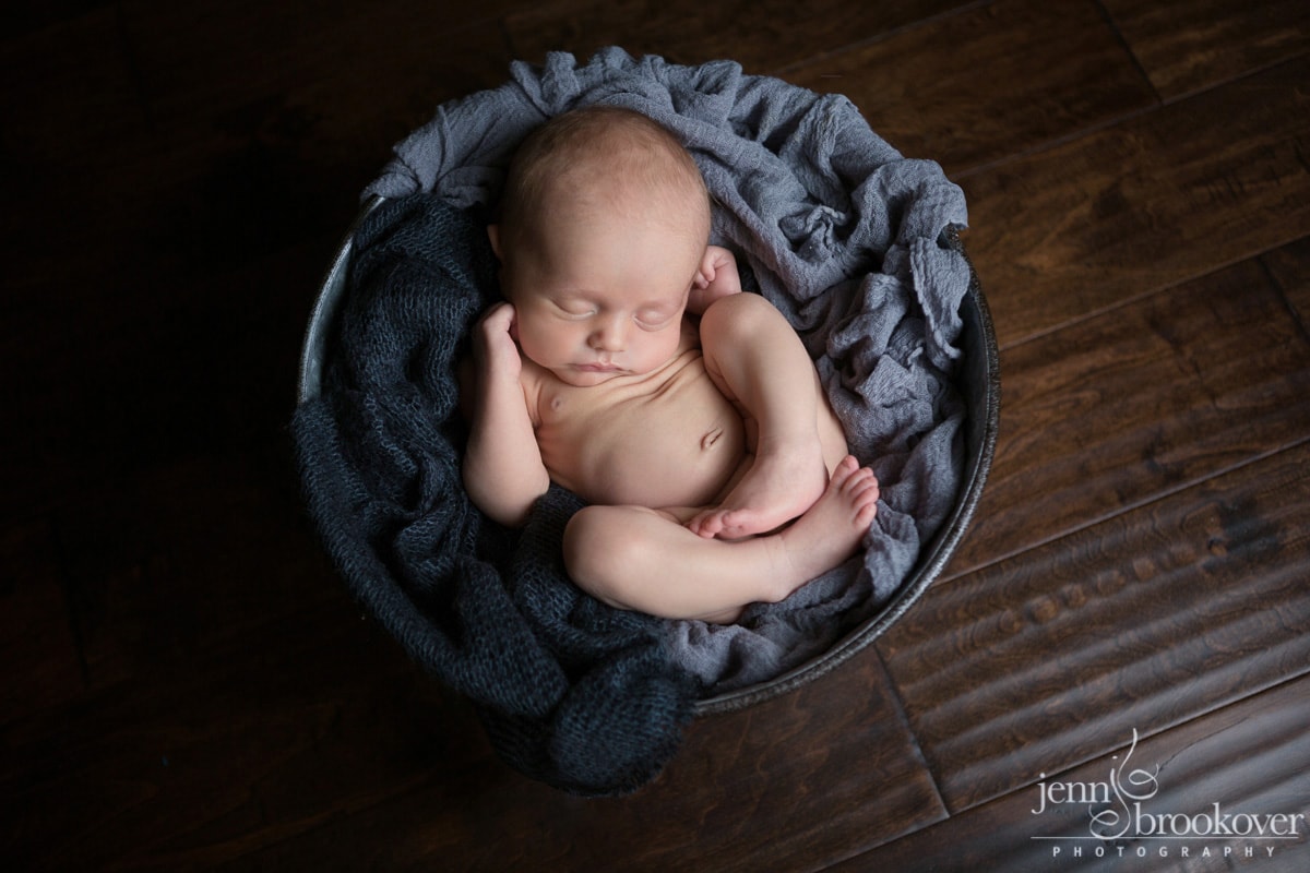 newborn boy asleep in a bucket during his portrait session with Jenn Brookover in San Antonio Texas