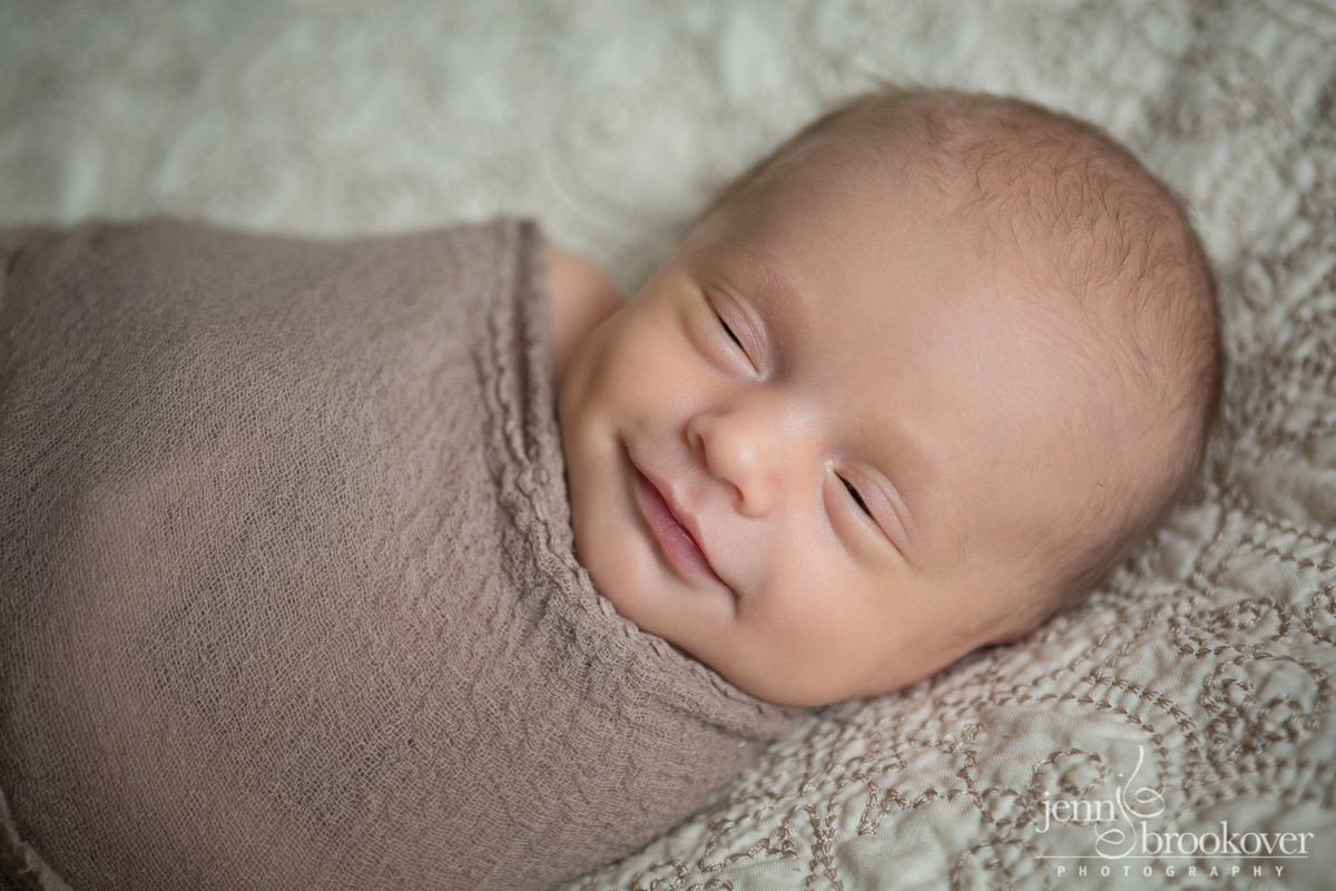 baby boy with sleepy smiles on his mom and dads bed in San Antonio taken by Jenn Brookover
