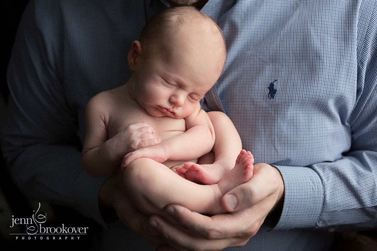 dad snuggling baby boy during newborn photo session at home in Alamo Heights Texas taken by Jenn Brookover