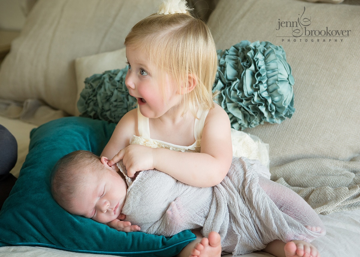 excited big sister snuggling with her baby brother