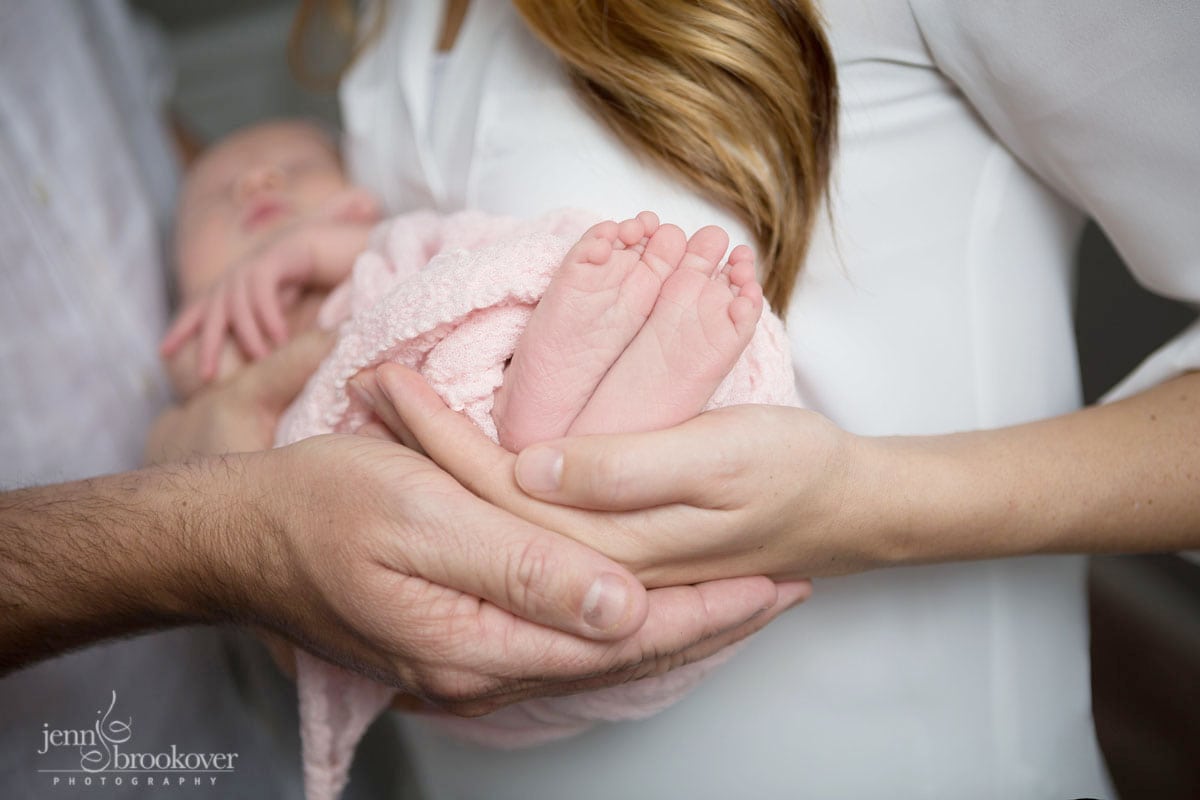 close up of baby feet and parent's hands taken during newborn session with Jenn Brookover