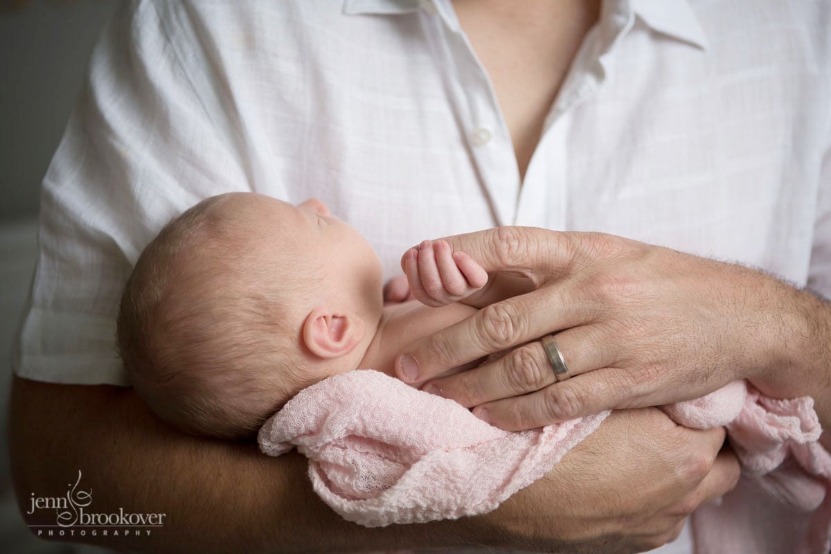 newborn fingers wrapped around dad's hands taken by Jenn Brookover