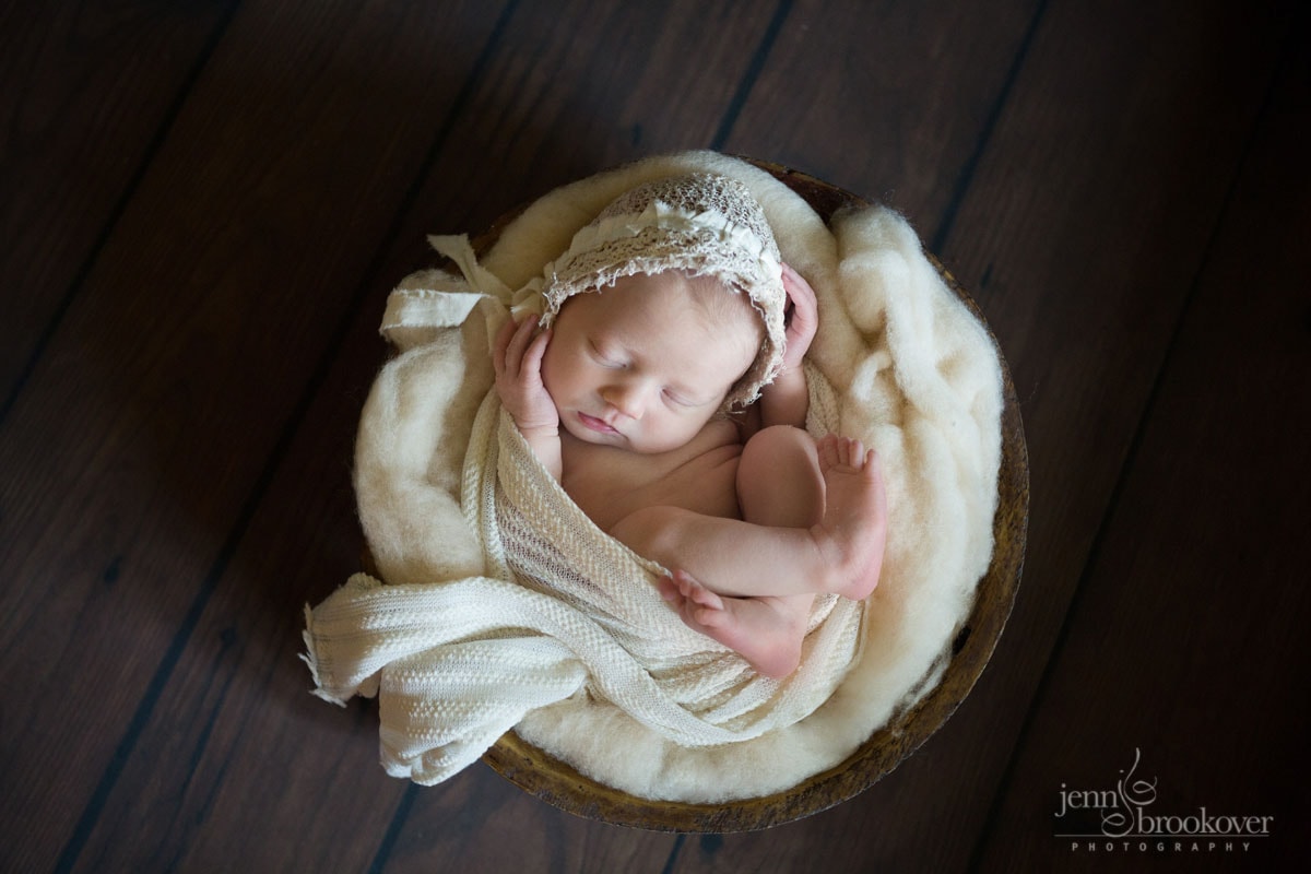newborn girl swaddled in cream fabric and wool wearing a lace bonnet taken by Jenn Brookover Photography in San Antonio