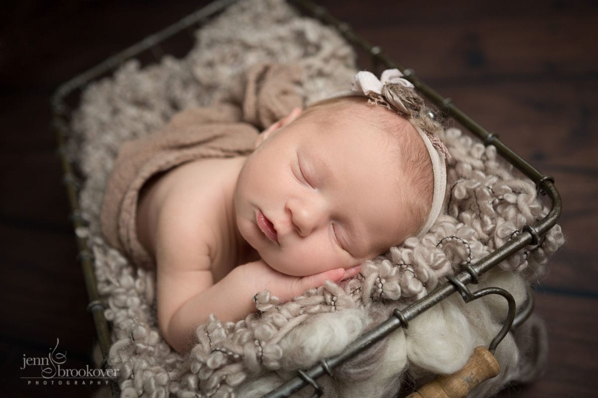 smiling newborn wrapped in taupe and sleeping for her newborn photo session at home with Jenn Brookover Photography in San Antonio