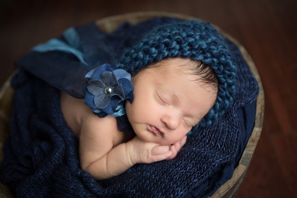 newborn baby girl in navy hat sleeping and smiling