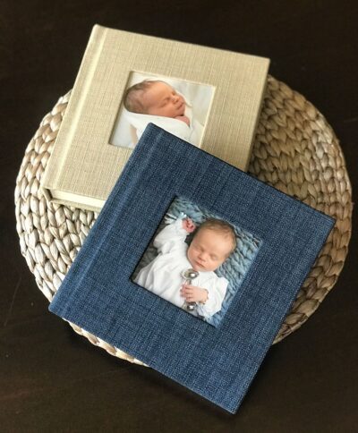 Two baby photo albums on a wicker basket.