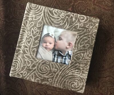 A baby is holding a photo in a frame.