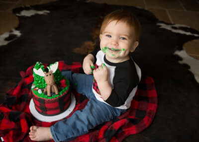 A baby boy is eating a christmas cake with reindeer on it.