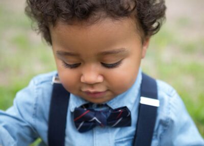 A young boy wearing a bow tie and suspenders.