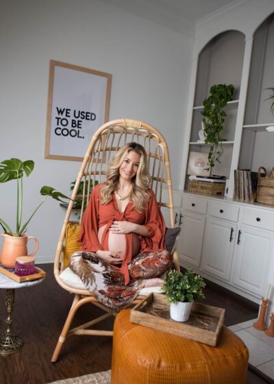 A pregnant woman sitting in a wicker chair in a living room.