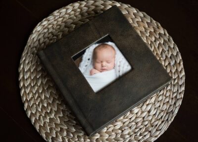 A photo of a baby in a black frame on a wicker basket.