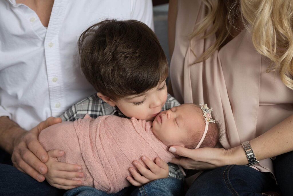 A family kisses their newborn baby.