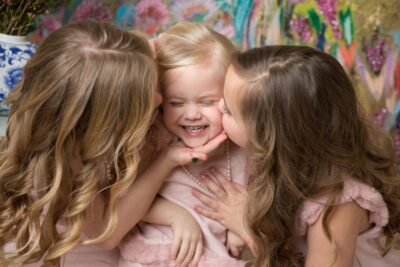 Three little girls hugging and kissing each other.