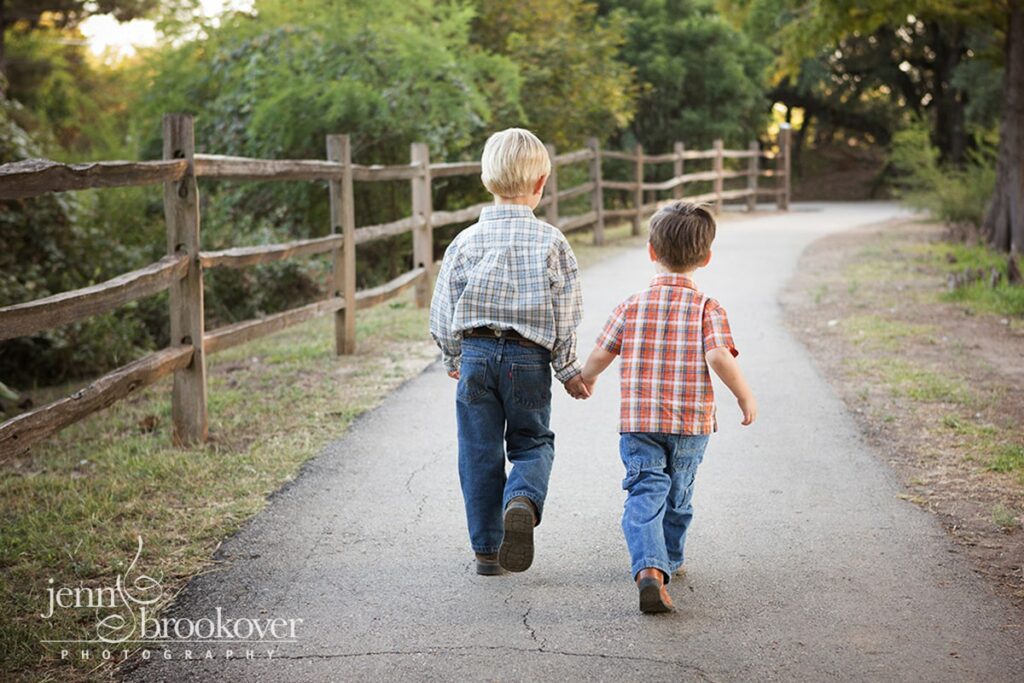 boys holding hands and walking down the path at Denman Estates Park during photo session