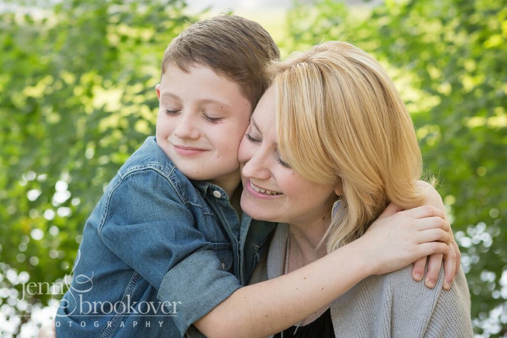 mom and son smiling and snuggling in the park at Denman Estates 