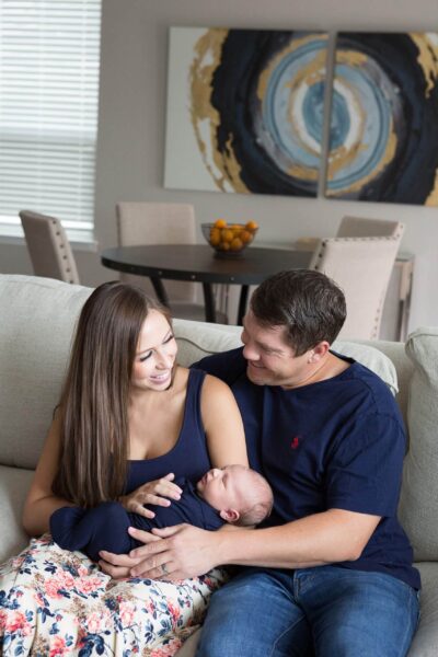 A man and woman sitting on a couch holding a baby.