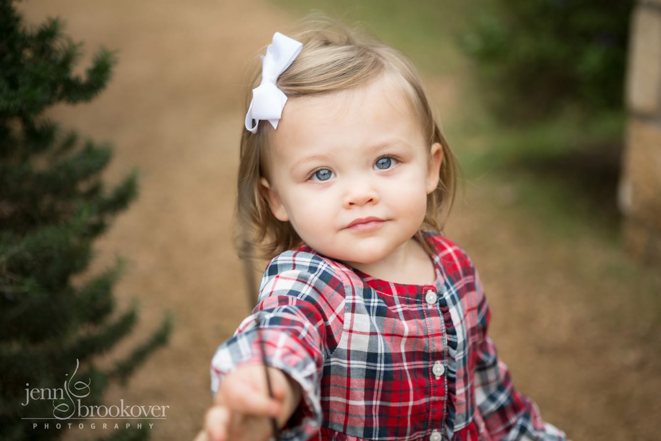 baby girl with blue eyes outside in red plaid outfit
