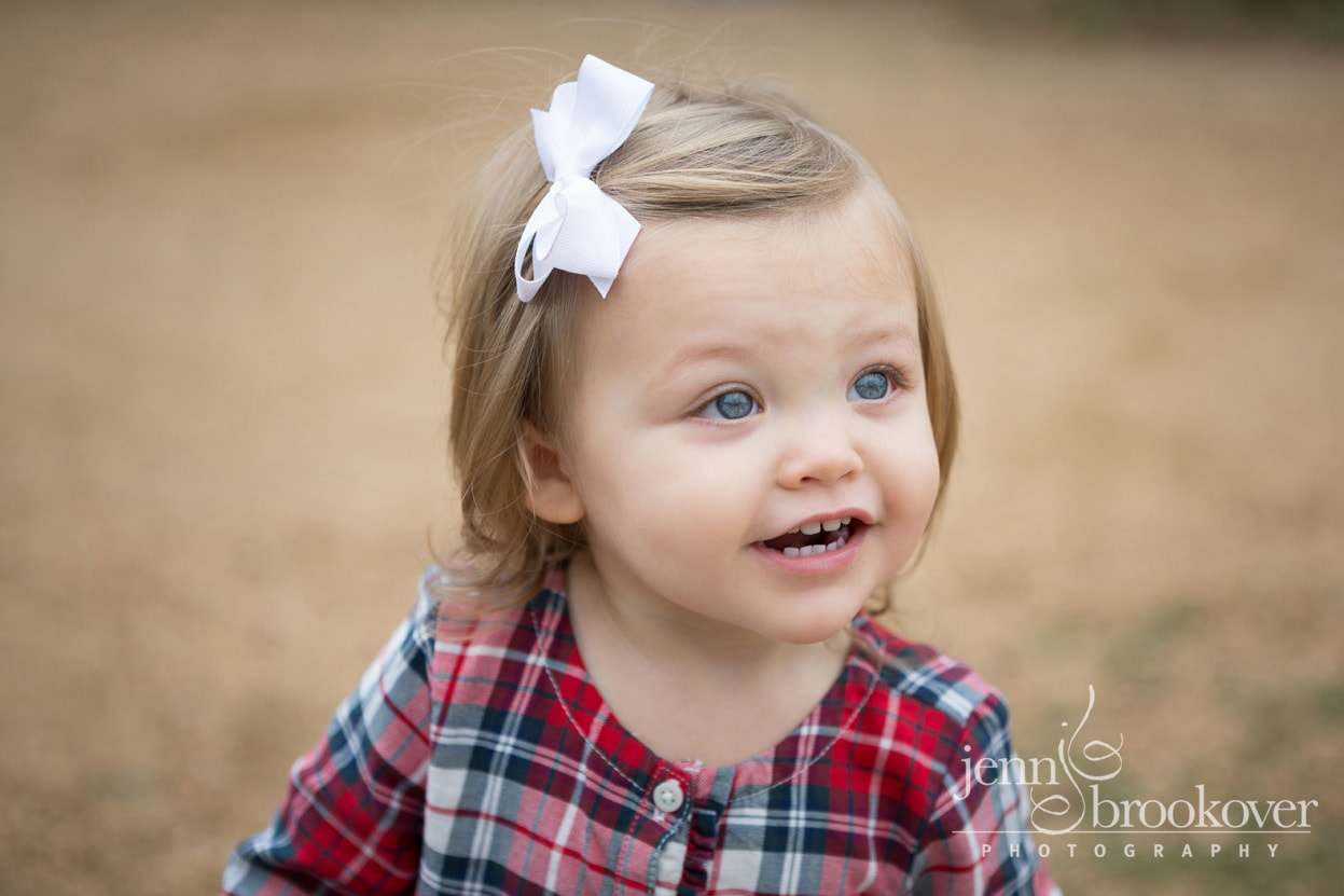 close up of two year old in plaid top and white bow taken at Tejas Rodeo