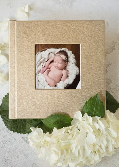 A photo of a newborn baby in a tan photo album.