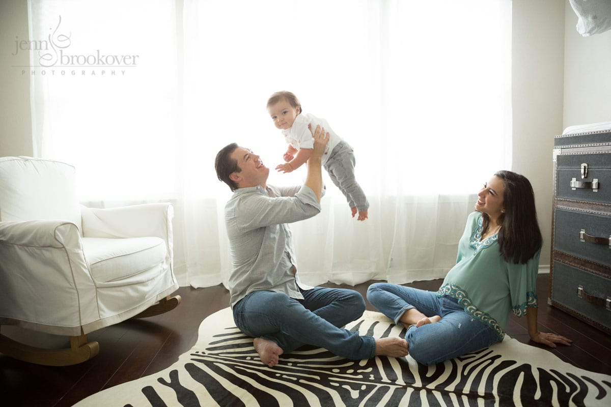 mom dad and toddler at home on a zebra rug during maternity session in San Antonio, Texas