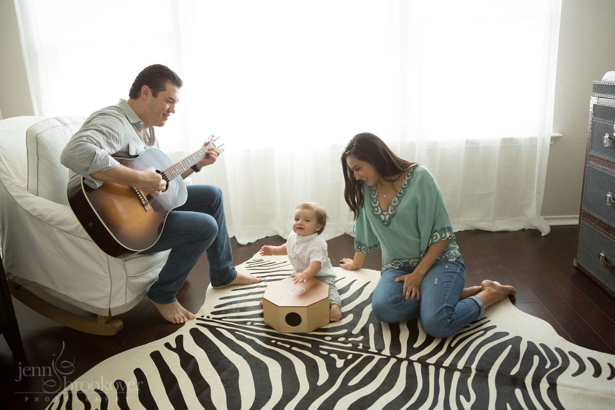 mom dad and toddler singing on a zebra rug in the nursery during maternity session in San Antonio, Texas