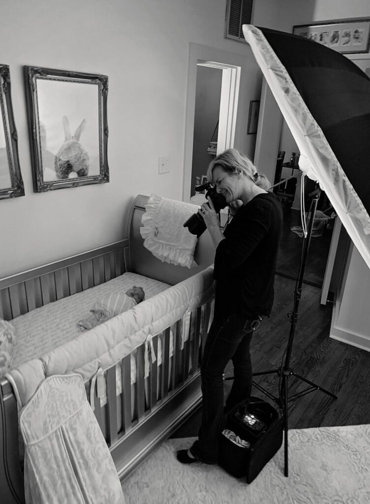 A woman is taking pictures of a baby in a crib.