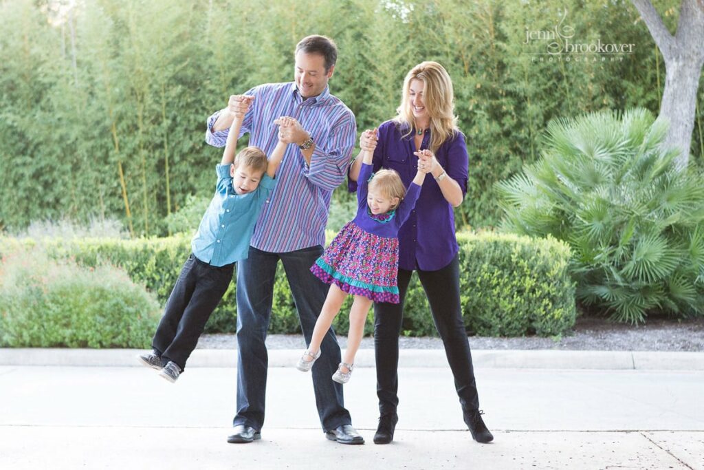 family laughing and swinging their children dressed in purple and teal at Landa Library 