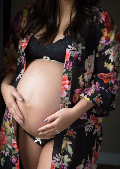A pregnant woman in a floral robe posing for a photo.