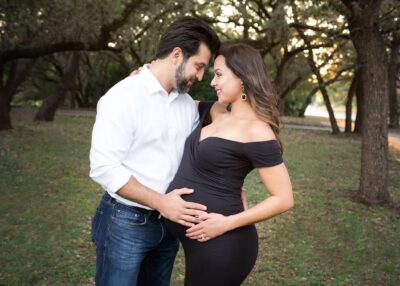 A pregnant couple embracing in a park.