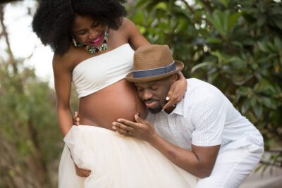 A pregnant woman is posing for a photo with her husband.