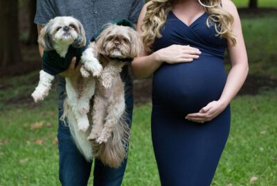 A pregnant woman and her husband pose with their dogs.