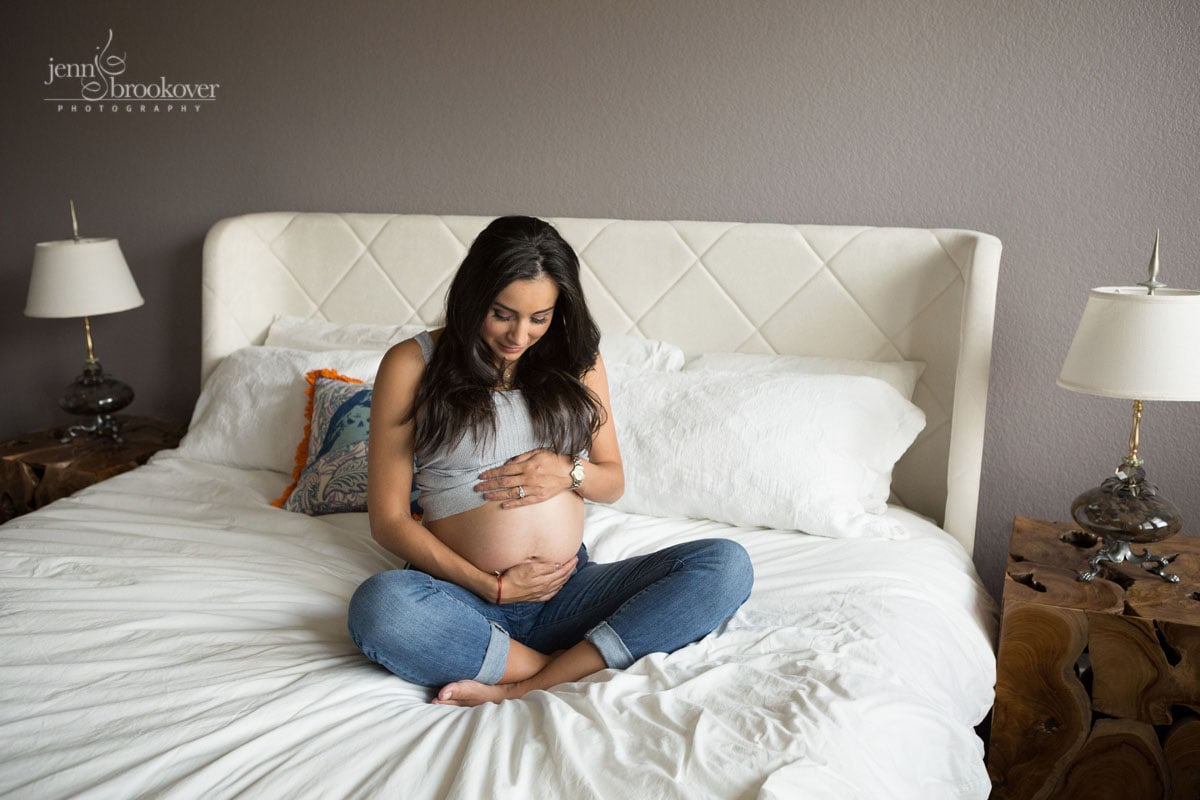mom lovingly holding belly during maternity session at home