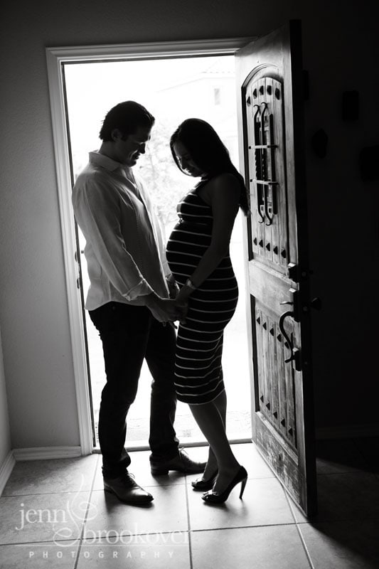 mom and dad backlit in doorway holding hands during their maternity photo session