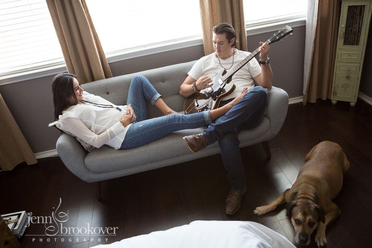 mom and dad on couch with dog during their at home maternity session 