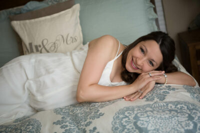 A pregnant woman laying on a bed smiling.