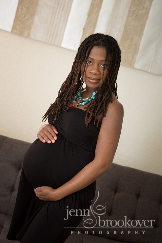 gorgeous mama in a black dress with turquoise necklace taken during her maternity photo shoot with Jenn Brookover