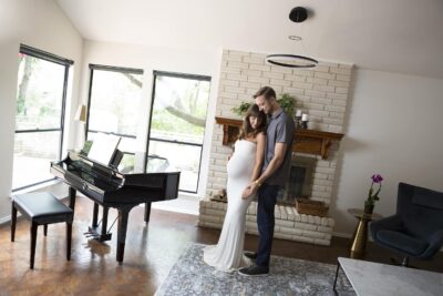 A couple standing in front of a piano in a living room.